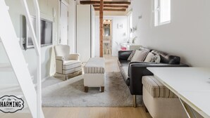 A modern living room with a wooden ceiling, a sofa, a chair, and a TV.