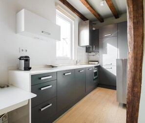 A modern kitchen with dark grey cabinets, a white countertop, and a built-in oven. - Reina Sofía II - Charming loft (Madrid)