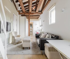 A modern living room with a wooden ceiling, a sofa, a chair, and a TV. - Reina Sofía II - Charming loft (Madrid)
