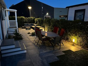 Une terrasse extérieure avec une table et des chaises, un porche blanc et un bâtiment en arrière-plan.