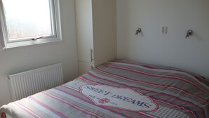 Un dormitorio con cama, ventana, radiador y puerta.