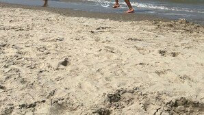 A beach with two people walking along the shore.