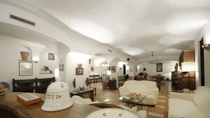 Ein geräumiges Wohnzimmer mit einem Holztisch, einem weißen Sofa und einem Essbereich im Hintergrund.