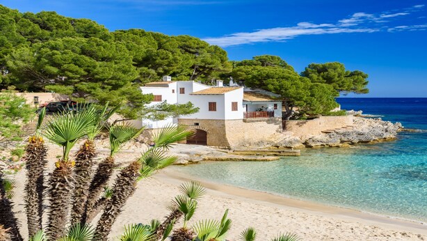 A coastal property with a white building, clear blue waters, and lush greenery.