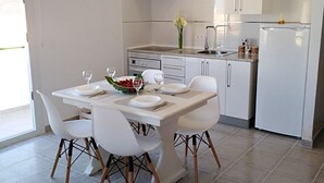A modern kitchen with white cabinets, a stainless steel range hood, and a dining area with a white table and chairs.
