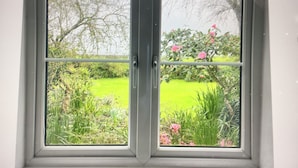 A window with a view of a green field and trees. - A beautiful 250 year old thatched cottage close to Frenchman's Creek. 2 bedrooms (Helston)