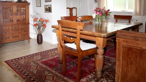 A dining area with a wooden table, chairs, a cabinet, and a patterned rug. - A beautiful 250 year old thatched cottage close to Frenchman's Creek. 2 bedrooms (Helston)