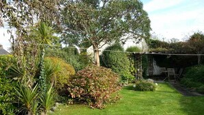 A lush garden with a variety of plants and a well-maintained lawn. - A beautiful 250 year old thatched cottage close to Frenchman's Creek. 2 bedrooms (Helston)
