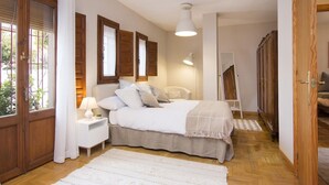 A bedroom with a bed, bedside tables, a lamp, a mirror, and a wardrobe.