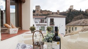 A table set for a meal with a bottle of wine, plates, and glasses, overlooking a historic town with ancient buildings.