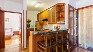Eine kompakte Küche mit Holzausstattung, einer Marmorarbeitsplatte und einer Essecke mit zwei Stühlen.