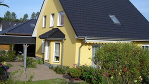 A yellow house with a dark roof, two windows, and a small porch. - Apartment in Bansin (Seebad Bansin)