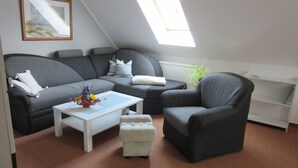 A cozy living room with a grey sofa, a white coffee table, and a grey armchair. - Apartment in Bansin (Seebad Bansin)