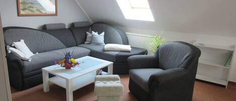 Ein gemütliches Wohnzimmer mit einem grauen Sofa, einem weißen Couchtisch und einem grauen Sessel.