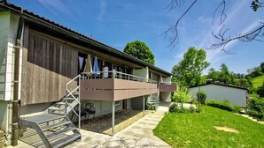 Ein zweigeschossiges Gebäude mit Balkon, Treppe und einem kleinen Garten.