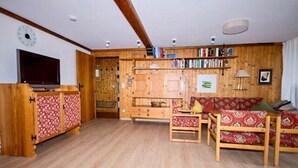 Ein Wohnzimmer mit einem TV-Schrank aus Holz, einer Couch und einem Bücherregal.