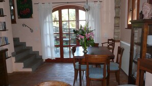 A dining area with a wooden table, chairs, and a vase of flowers. There is a staircase leading to another room, and a bookshelf with books. - Convert your vacation into a highly regenerating life experience. (Pontassieve)