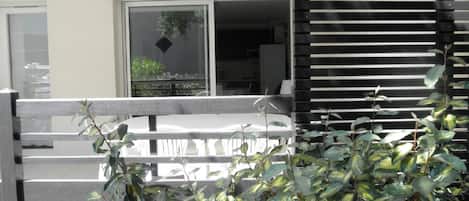 Un balcón con vista al interior de un edificio, una ventana y una planta al frente.
