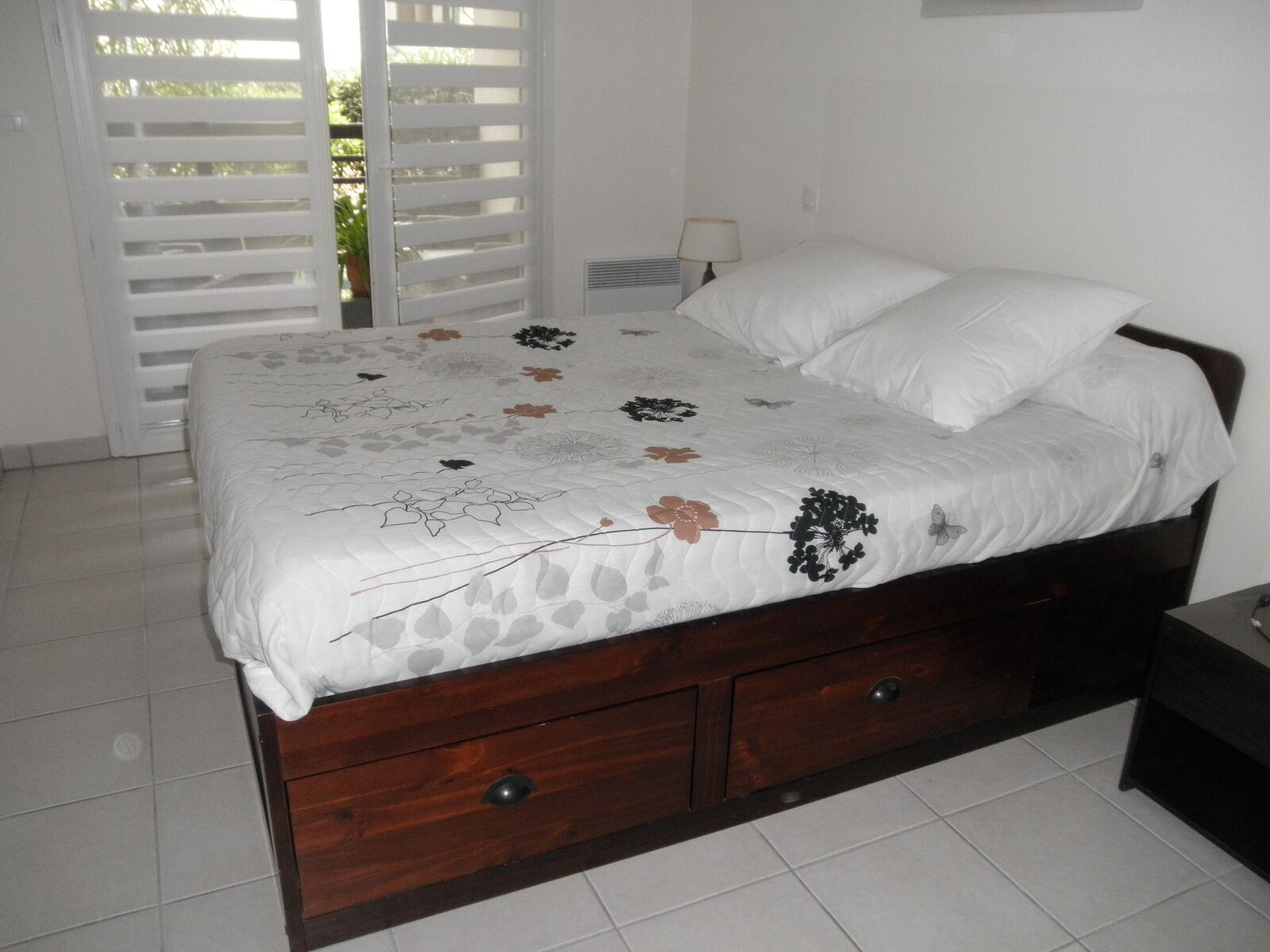 Une chambre à coucher avec un lit, une table de chevet, une lampe et une porte coulissante.