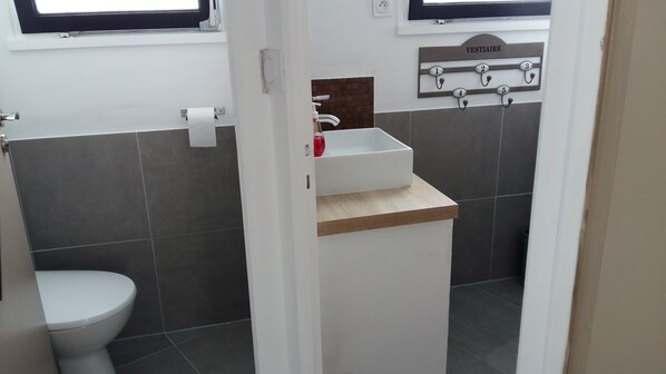 A bathroom with a toilet, a sink with a mirror, and a towel rack.