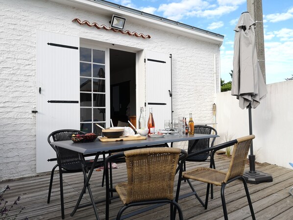 An outdoor dining area with a white building, a table set with chairs, and a pergola with a canopy. - 2-bedroom house, close to the beach, all on foot (L'aiguillon-Sur-Mer)