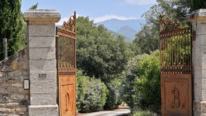 Una porta de pedra amb una fusta, un mur de pedra amb una placa de número, i vista d'un paisatge montanyós.