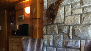 A cozy room with a stone wall, wooden furniture, and a television.
