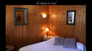 A wooden-paneled room with a bed, a nightstand with a lamp, and a framed picture on the wall.