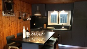 A modern kitchen with a central island, bar stools, and a wine bottle.