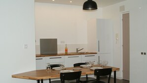 Een moderne keuken met witte kastjes, een houten aanrecht en een eettafel gedekt voor vier personen.
