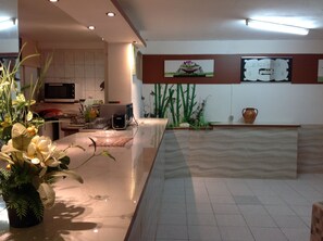Welcome to our reception area, featuring a sleek counter, a potted plant, and framed artwork.