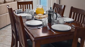 A dining area with a wooden table set for breakfast, a coffee maker, and a view of the ocean. - Beach Front Condo, Spacious, Clean and Comfortable (Gulf Shores)