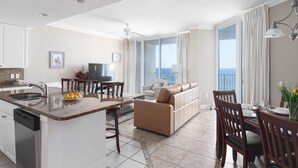 A spacious living area with a kitchen island, a sofa, and a dining table with chairs. - Beach Front Condo, Spacious, Clean and Comfortable (Gulf Shores)