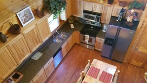A compact kitchen with wooden cabinets, a microwave, stove, and refrigerator. - Big Nate Cabin on Lake with Water Trampoline (Hiawassee)