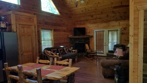 A wooden cabin interior with a dining area, living room, and fireplace. - Big Nate Cabin on Lake with Water Trampoline (Hiawassee)