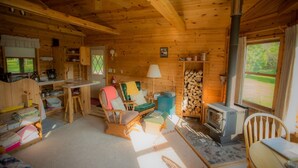 Een gezellig chaletinterieur met houten details, een open haard, een eethoek en een keuken.