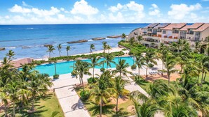 Un complexe hôtelier doté d’une piscine, de palmiers et offrant une vue sur l’océan.
