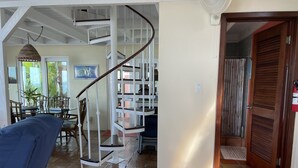 A spacious living area with a spiral staircase, a dining area with wooden furniture, and a view of the outdoors. - Coconuts: Indoor/Outdoor Living, Spa, Heated Pool & Privacy! (St. John)