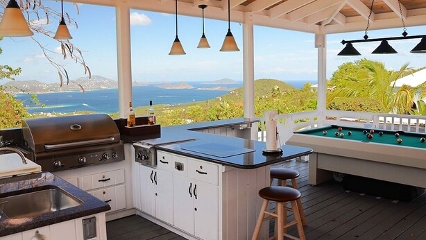 An outdoor kitchen with a grill, bar area, and pool table, overlooking a scenic view. - Coconuts: Indoor/Outdoor Living, Spa, Heated Pool & Privacy! (St. John)