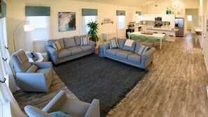 A spacious living room with two sofas, a coffee table, and a dining area with a kitchen in the background. - Beachfront! 4bdr(3 kings)/3 bath/sleeps  17  (Surfside Beach)