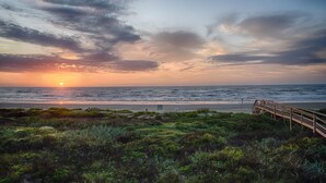 A sunset over the ocean with a wooden boardwalk leading to a beach. - Beachfront! 4bdr(3 kings)/3 bath/sleeps  17  (Surfside Beach)