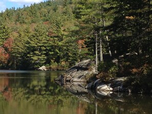 A serene lake surrounded by dense forest with a rocky shoreline.
