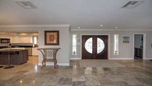 A spacious kitchen with modern appliances, a dining area with a table and chairs, and a large double door with a stained glass window.
