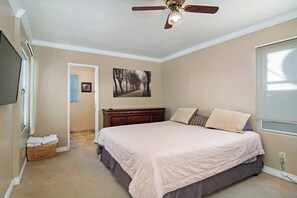 Una camera da letto con un letto grande, una ventola a soffitto, un quadro al muro e una finestra con tende.