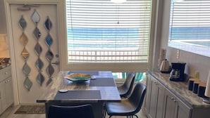 Eine moderne Küche mit Essbereich, mit Marmorarbeitsplatte, schwarzen Stühlen und Deckenventilator.