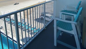 Ein Balkon mit Blick auf den Strand, einen Pool und Liegestühle.