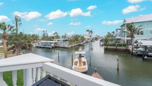 A canal with a boat, waterfront buildings, and palm trees. - Zénith Retreat steps from the sugary sand (Fort Myers Beach)