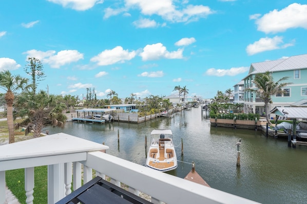 A canal with a boat, waterfront buildings, and palm trees.