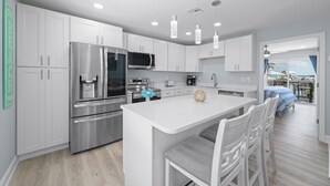 A modern kitchen with white cabinetry, stainless steel appliances, and pendant lighting. - Zénith Retreat steps from the sugary sand (Fort Myers Beach)