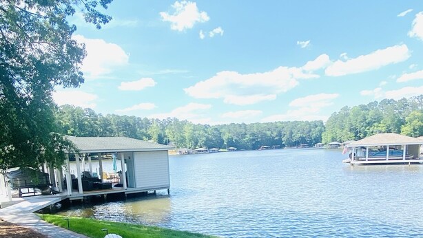 Terraza junto al lago con sillas Adirondack, un pozo de fuego y vistas del lago y barcos amarrados.